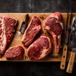 a cutting board with steaks and a knife on it