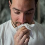 man wiping nose with tissue paper