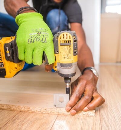 Person Using Dewalt Cordless Impact Driver on Brown Board