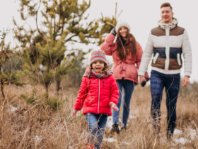 Young family together walking in forest at winter time