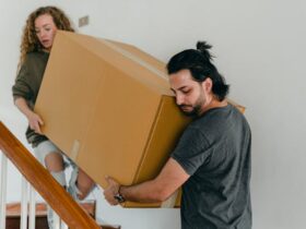 Concentrated couple carrying big carton box down stairs